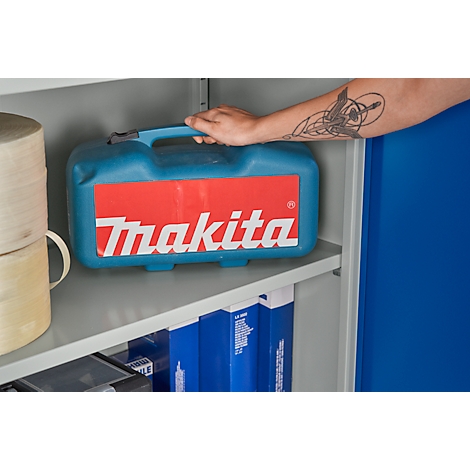 Persoon die een blauwe gereedschapskist met rood Makita-logo in een plank vasthoudt.