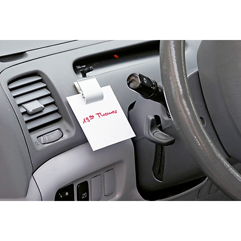 Note with red text, clip in car. Steering wheel, dashboard.