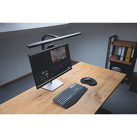 Gros plan d'une lampe de bureau noire avec trois petits boutons au milieu et deux entretoises noires. Le fond est gris clair.