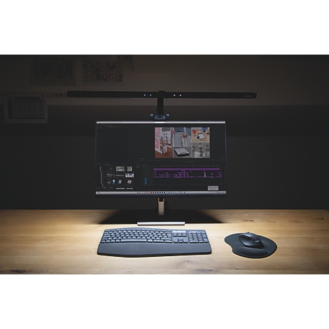 Bureau avec moniteur, clavier, souris et lampe. Dans le fond, une étagère avec des dossiers.