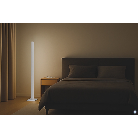 Schlafzimmer mit Stehlampe: Helles Licht neben Bett mit dunkler Bettwäsche. Nachttisch mit Glas.