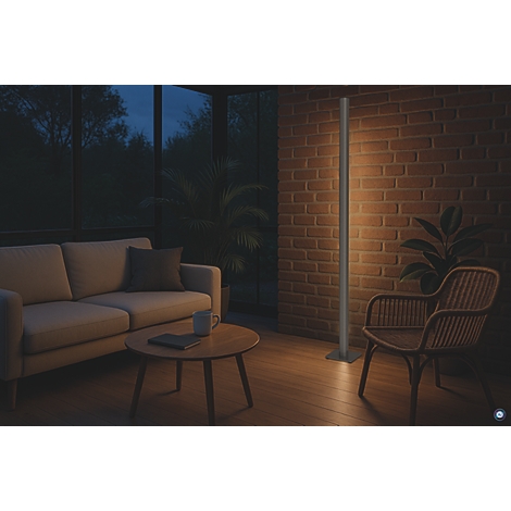 Stehlampe beleuchtet einen Wohnbereich mit Couch, Sessel und Backsteinmauer. Dunkle Umgebung mit warmem Licht.