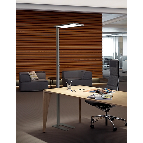 Moderne Stehleuchte neben einem hellen Holztisch in einem stilvollen Büro mit Holzlamellenwand.