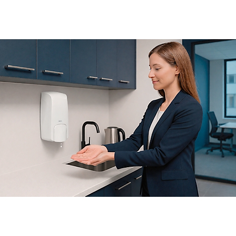 Frau in blauem Blazer, wäscht sich die Hände. Über dem Waschbecken ein weißer Seifenspender.