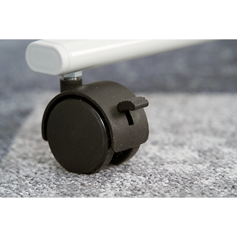 Close-up of a black furniture wheel with locking lever. On a gray surface.