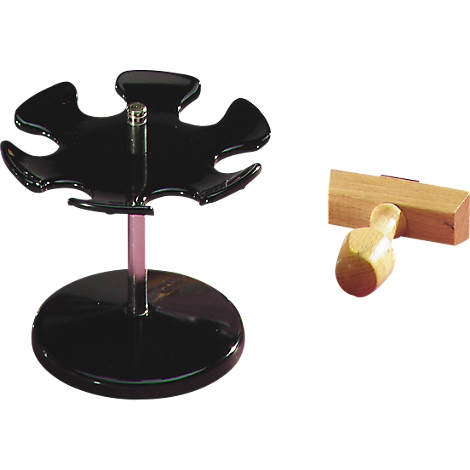 Black pen holder and wooden stamp. The pen holder has a round base, a pink rod, and a flower-shaped holder. The stamp is light.