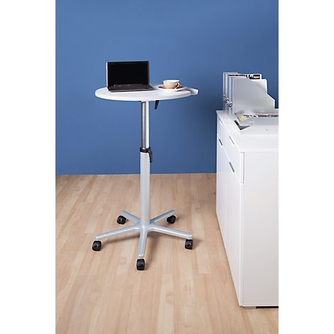 Small, white standing desk with laptop and coffee cup. Wheels on the base. Blue background. Light wood parquet.