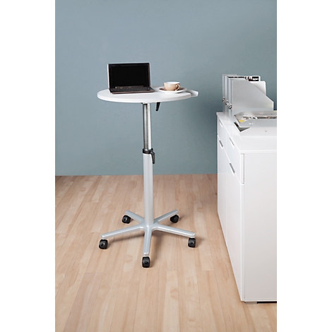 Small white standing desk with laptop and cup, on wheels. A white cabinet is next to it.