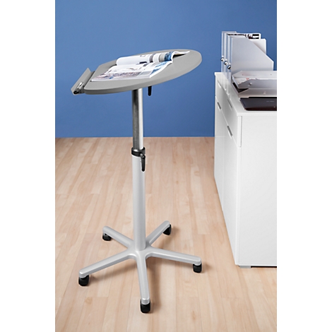 Grey standing table with magazines, in front of blue wall and white cabinet. On light wooden floor.