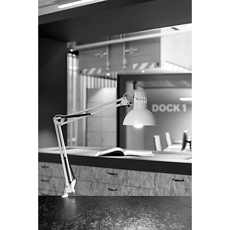Een witte bureaulamp verlicht een boek op een bureau. Op de achtergrond is een kamer met de inscriptie "DOCK1".