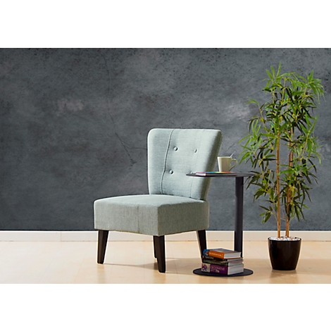 Lichtblauwe fauteuil naast een bijzettafel met een kopje, daarnaast een plant voor een grijze muur.