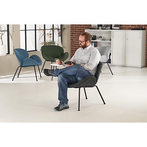 Un homme est assis détendu sur une chaise design grise. En arrière-plan, d'autres chaises et meubles.