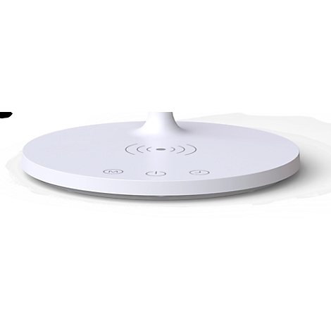 Gros plan sur une lampe de bureau blanche. Des symboles de chargement sans fil et de commandes sont sur la base.