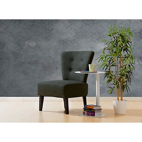 Fauteuil gris foncé à côté d'une petite table avec des livres et une tasse. À côté, une plante de bambou.