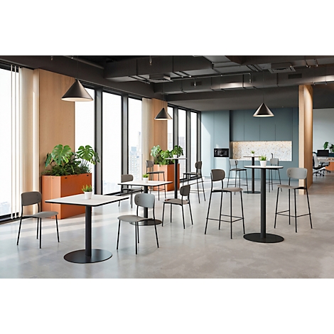 Un espace de bureau ouvert avec des tables et des chaises, de grandes fenêtres, des plantes et un décor minimaliste.