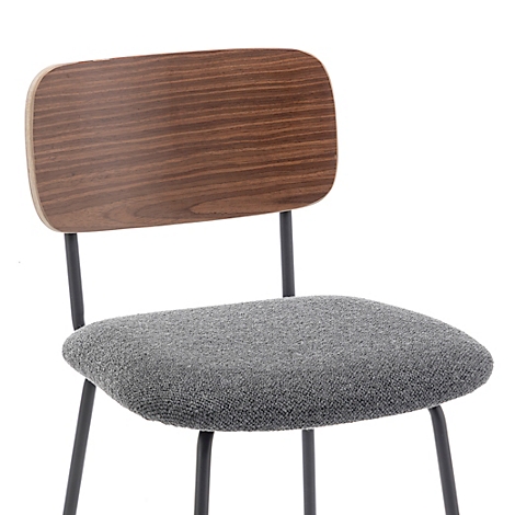 Gros plan d'une chaise. Dossier en bois, assise grise, cadre noir. La chaise est contre un fond blanc.