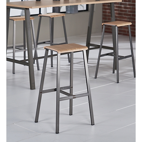Stools with wooden seats and metal frames in front of a table. Brick wall in the background.