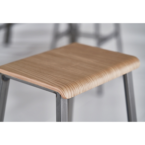 Stool with wooden top. Grainy plate, rounded edges. Metal legs, close-up.