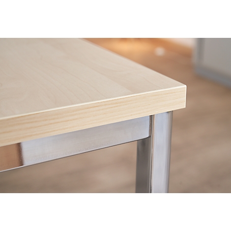 Close-up of a light wood table top, on a silver-colored leg.