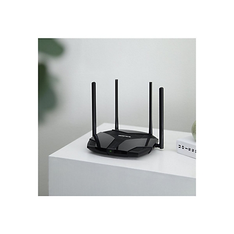 Routeur wifi noir avec quatre antennes sur une table blanche. A côté, un livre, en arrière-plan, une plante.