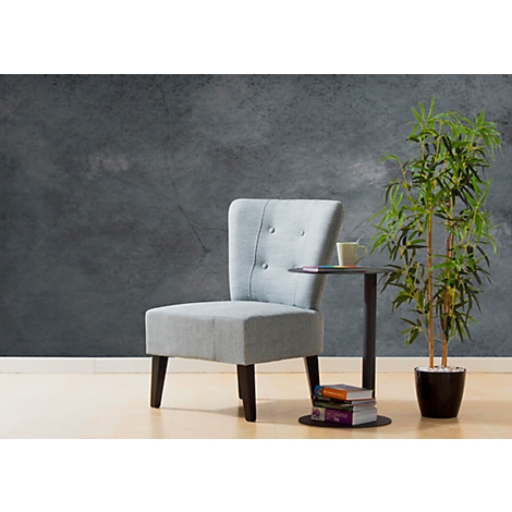 Sillón azul claro junto a una mesa auxiliar y una planta de interior. El fondo es gris.