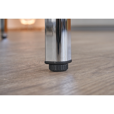 Primer plano de una pata de mesa plateada con pie negro sobre suelo de madera clara.