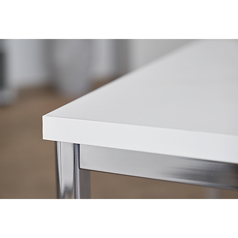 Primer plano de una mesa blanca con patas plateadas. El borde de la mesa está enfocado.