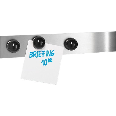 Magnetic metal strip with black magnets holding a white memo with blue text. The memo says: BRIEFING 10:00.