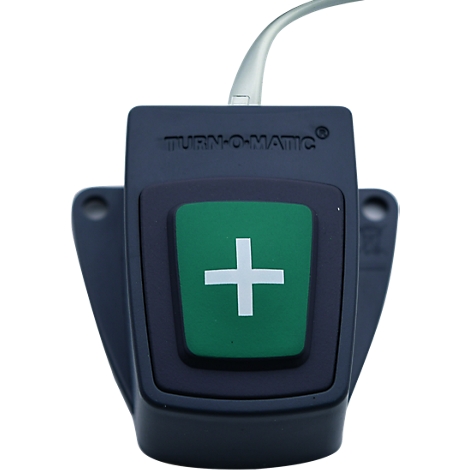 Appareil gris foncé avec bouton vert avec signe plus blanc. Il est écrit 'TURN-O-MATIC'. Un câble s'en va.