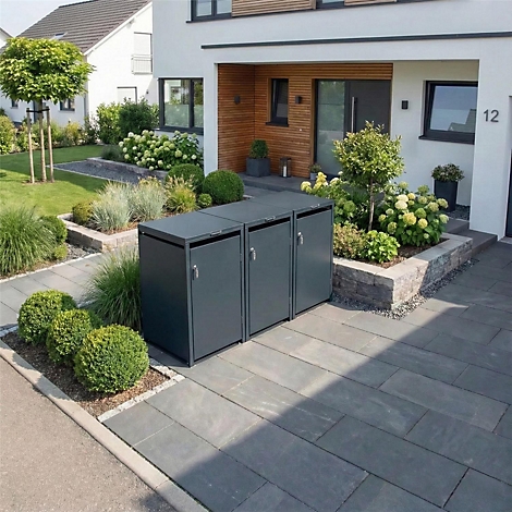 Drie grijze vuilnisbakken voor een modern huis. Geplaveide weg, tuin met struiken en bomen.