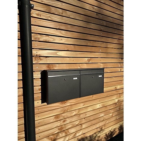 Deux boîtes aux lettres noires sur une façade en bois. A droite, une gouttière noire.