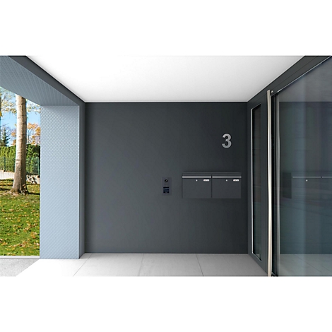 Mur de maison gris foncé avec le numéro 3, une boîte aux lettres et une sonnette. À gauche, un espace d'entrée avec espace vert est visible.