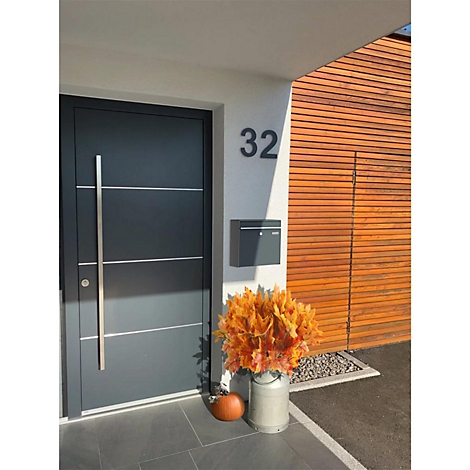 Porte d'entrée grise avec poignée en acier inoxydable et numéro de maison 32. Citrouille et décorations d'automne devant.
