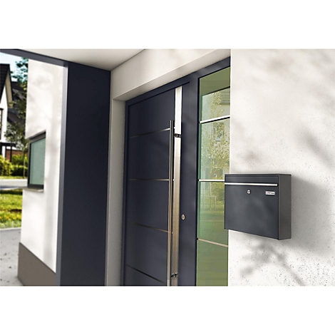 Boîte aux lettres noire sur le mur de la maison, à côté de la porte d'entrée.