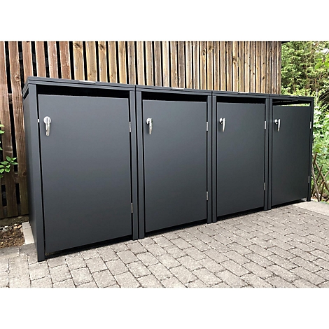Poubelles grises sur des pavés, devant un mur en bois.