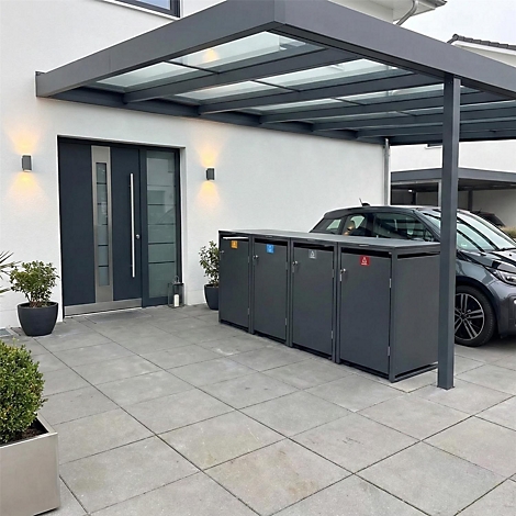 Dunkelgraue Mülltonnenbox unter einem Carport, vor einer Haustür. Das Bild ist aus der Perspektive des Betrachters aufgenommen.