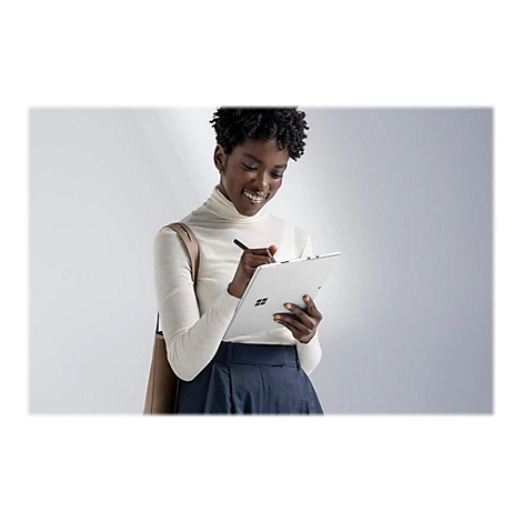 Femme souriante Ã©crivant sur une tablette avec un stylo. Portant un col roulÃ© et une jupe, avec un sac marron.