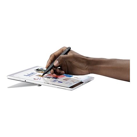 Une main sombre utilise un stylo noir sur une tablette affichant un magazine.