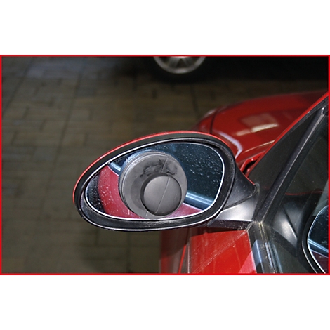 Nahaufnahme eines roten Autospiegels mit schwarzem Objekt.