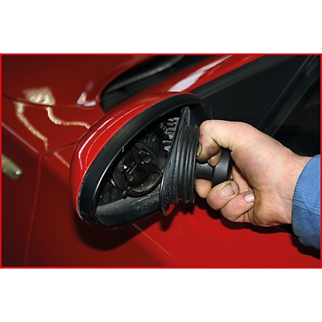 Ein Mann hält ein schwarzes Teil eines roten Autos.