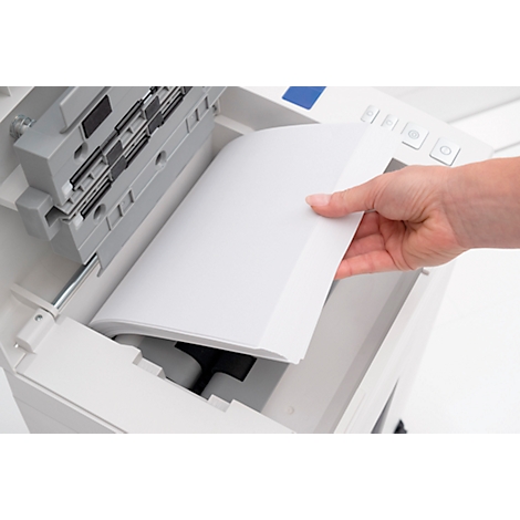 Hand placing paper into a printer. The printer is white, and the paper is blank.