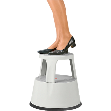 Legs on a white step stool, black shoes. Assistance for everyday life or work.