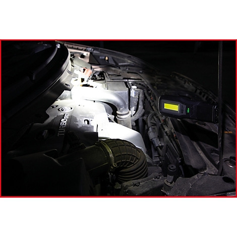 Motorraum mit einer Taschenlampe beleuchtet, Teile des Motors sind sichtbar. Das Wort Turbo ist erkennbar.