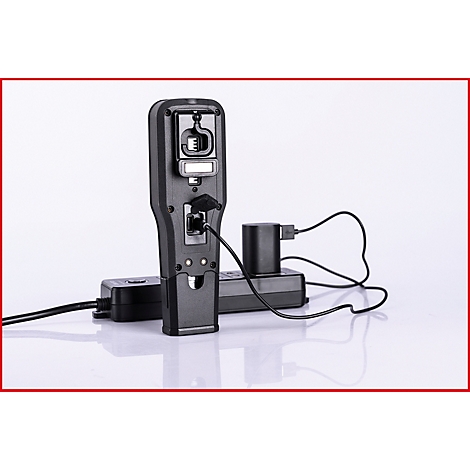Ein schwarzes mobiles Gerät steht mit Ladegerät vor weißem Hintergrund. Kabel sind angeschlossen.