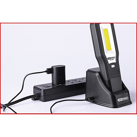 Schwarze LED-Arbeitsleuchte in Ladestation. Steckerleiste mit Stecker verbunden.