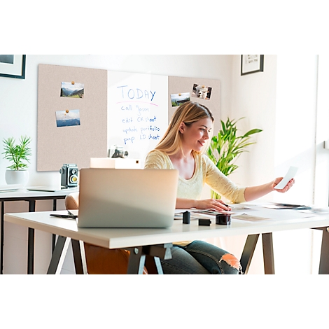 Une femme souriante est assise à un bureau avec un ordinateur portable et des photos qu'elle regarde.