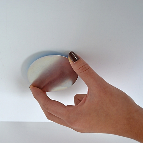 Zwei runde, flache Metallplatten mit einer glatten Oberfläche. Die obere Platte hat eine geschliffene Oberfläche, die untere Platte weist zwei kleine Magneten auf.