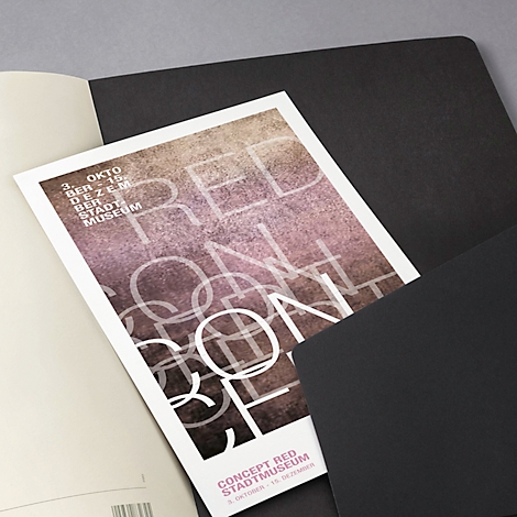 Poster with the words "RED CONCEPT" on notebooks. Black sheets and gray background. Date top left: 3 October to 15 December.