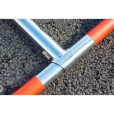 Metal pipe connector with orange ends on dark asphalt.