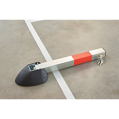 A silver parking bollard, partially orange and red, lies on a parking space. Also visible in the picture are a white line and keys.